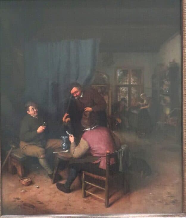 Seventeenth-century painting of a tavern interior: three men in rough clothes drink and smoke around a small table, a pewter jug between them, with a woman and a window in the lit room beyond