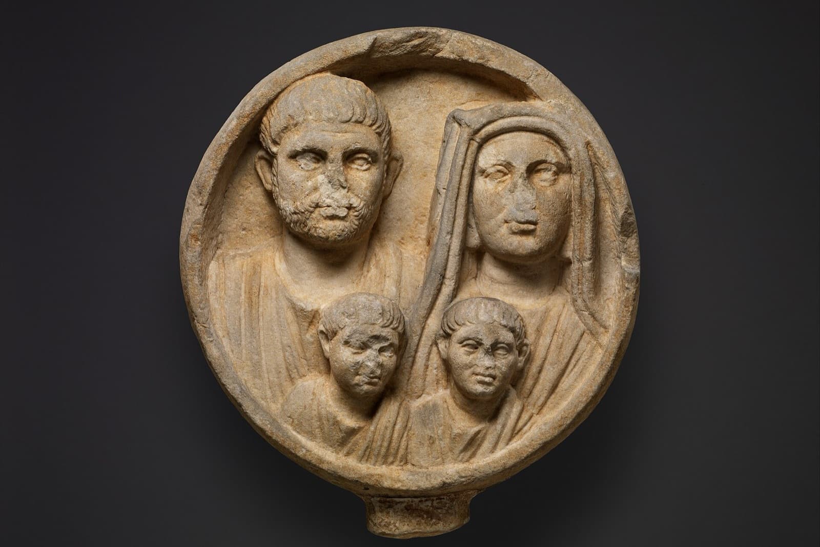 Round marble relief of a Roman family: a bearded father and a veiled mother, with two young sons in front of them